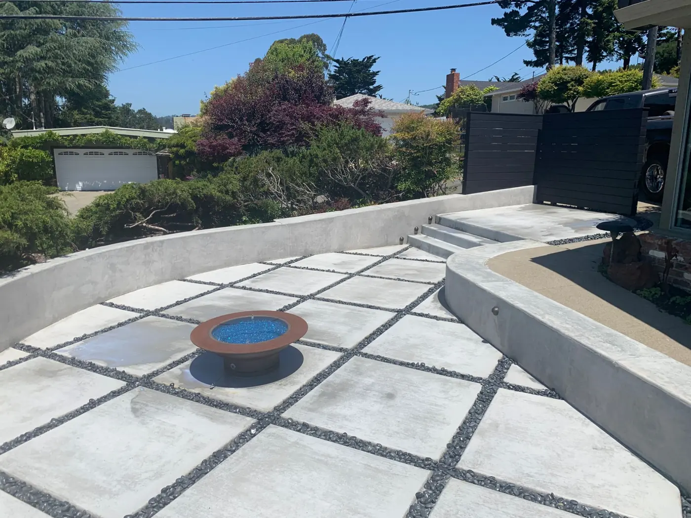Concrete patio with a fire pit and seating wall